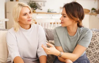 Younger woman supporting an older woman during a thoughtful conversation at home