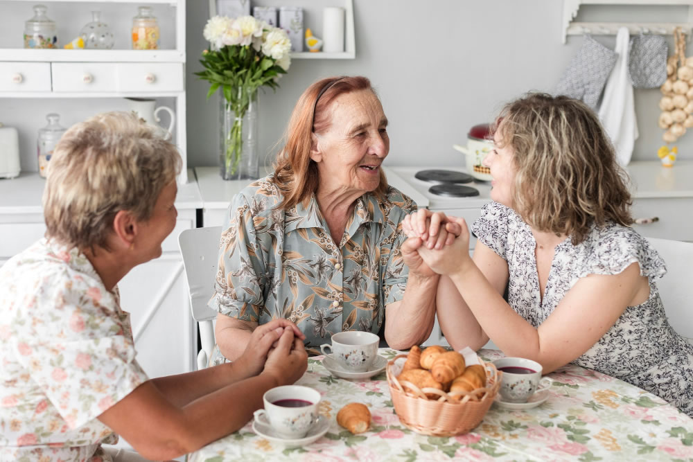 People sitting around a kitchen table sharing conversation and connection during a Dying to Know Day discussion about end-of-life planning.