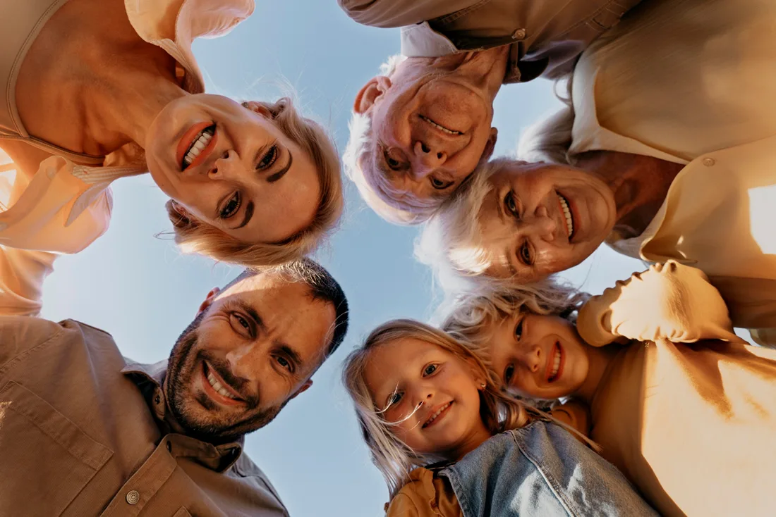 Multigenerational family members looking down together and smiling outdoors