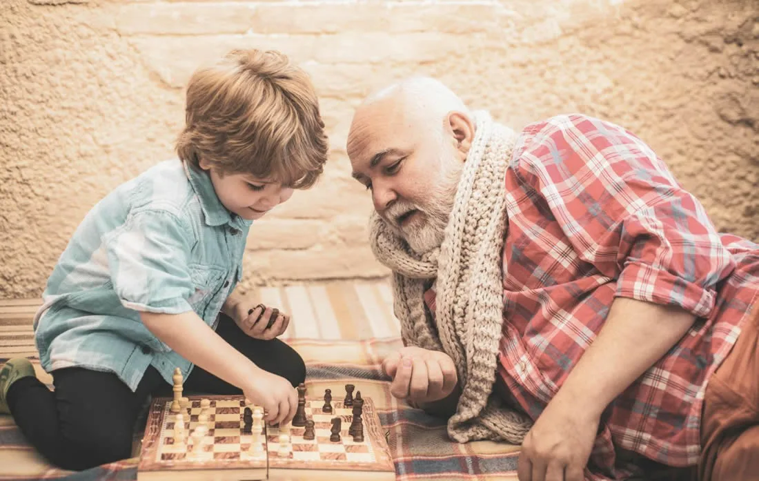 Older Australians Sharing Knowledge Across Generations Grandfather teaching his grandson how to play chess.