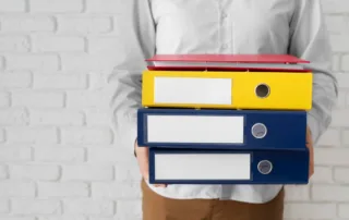 Person holding organised folders representing practical planning and important personal information during palliative care and serious illness.