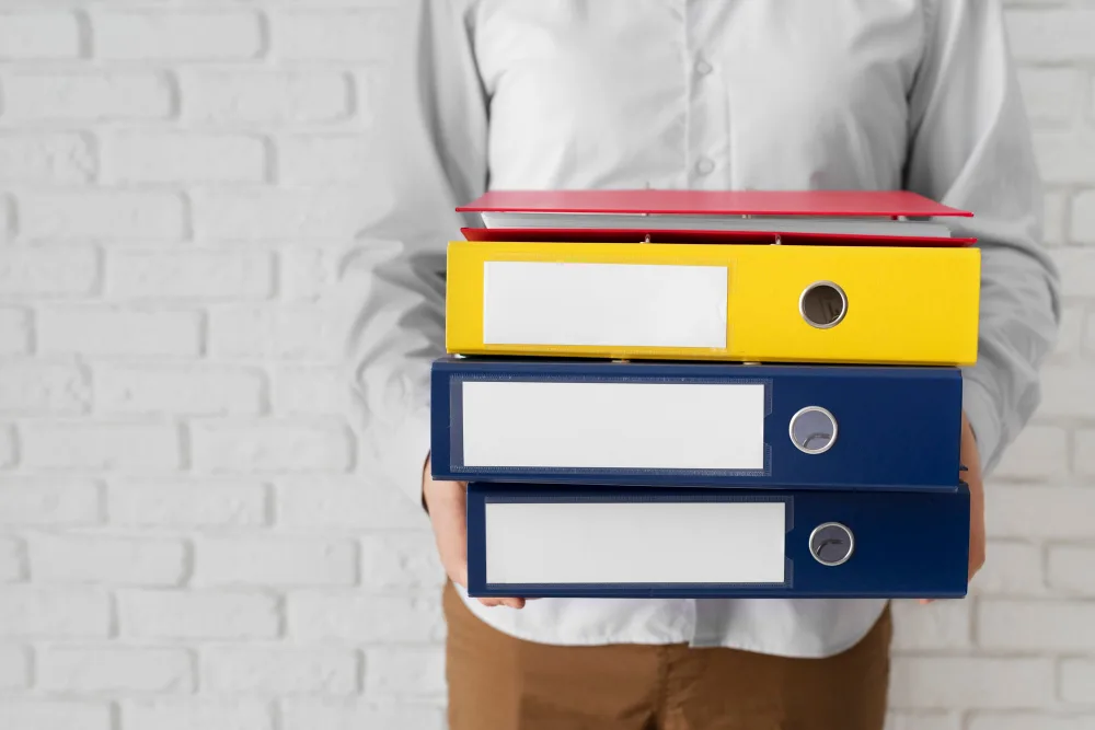 Person holding organised folders representing practical planning and important personal information during palliative care and serious illness. Person holding organised folders representing practical planning and important personal information during palliative care and serious illness.