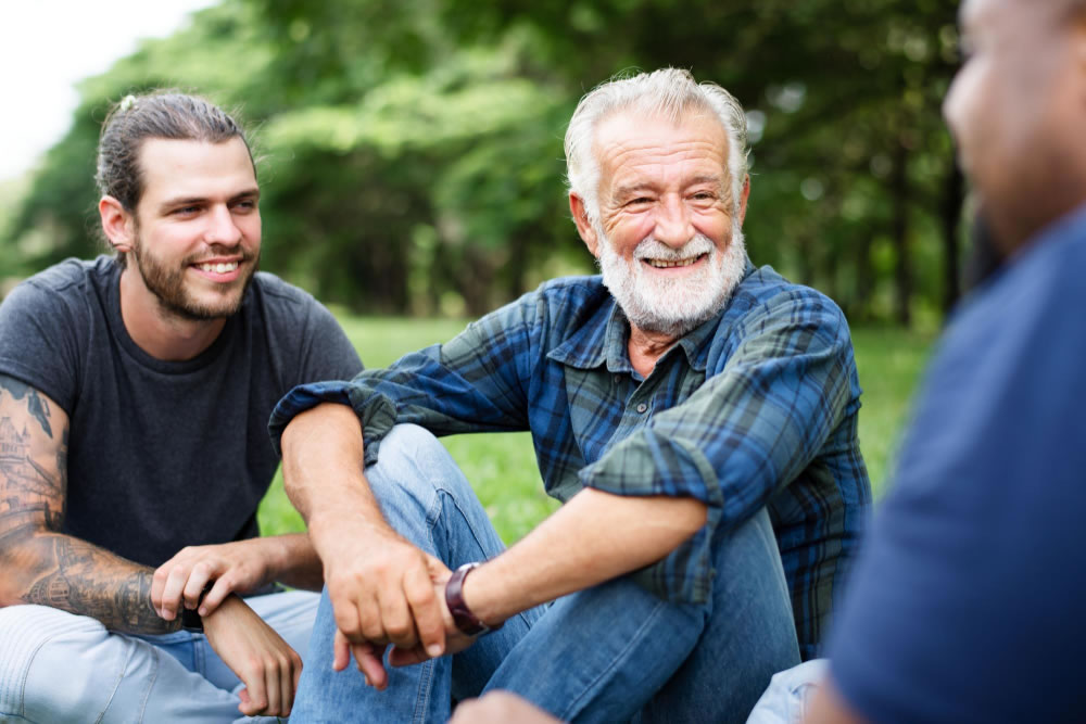 Men sitting together outdoors, talking and supporting each other during Prostate Cancer Awareness Month.