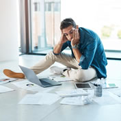 A person surrounded by scattered paperwork and documents, illustrating the confusion families can face when important information hasn’t been organised in advance.