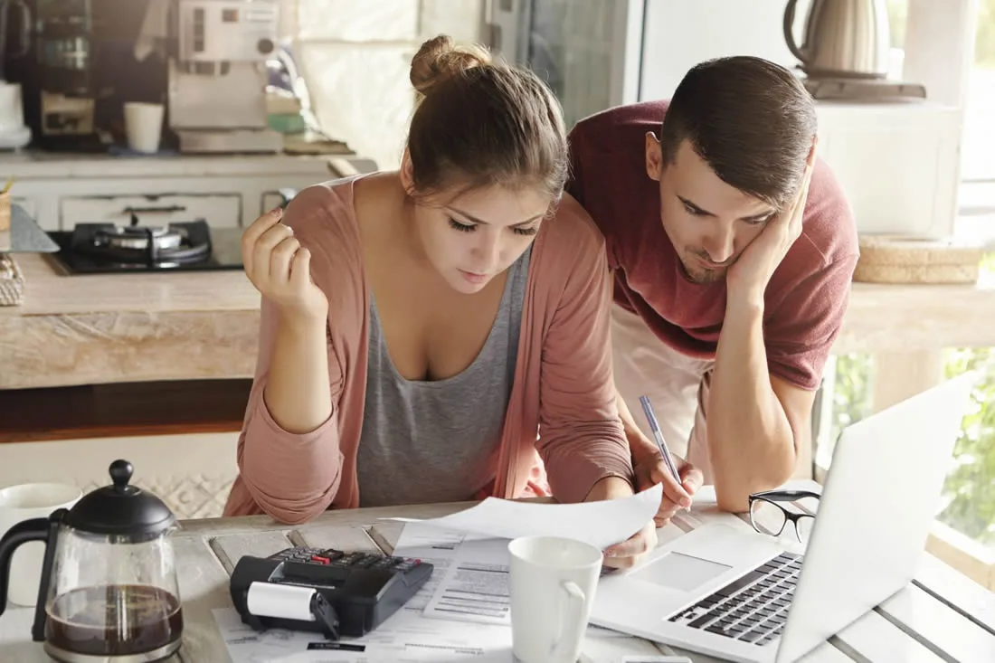 Couple reviewing household bills and expenses following an unexpected interruption to work.