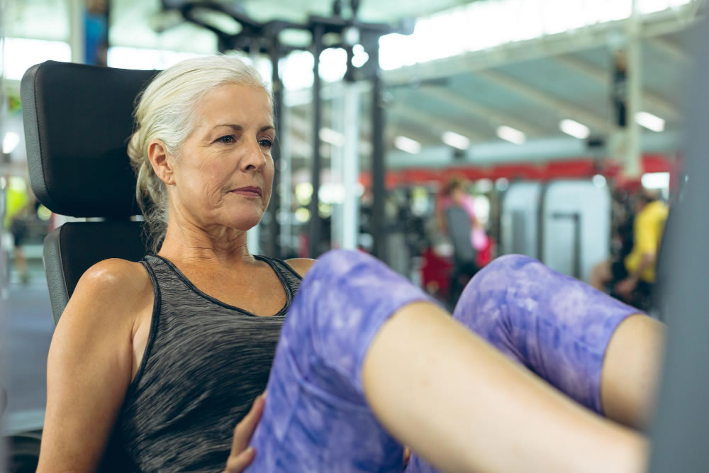 Older woman using resistance exercise equipment to improve bone strength and reduce osteoporosis risk.